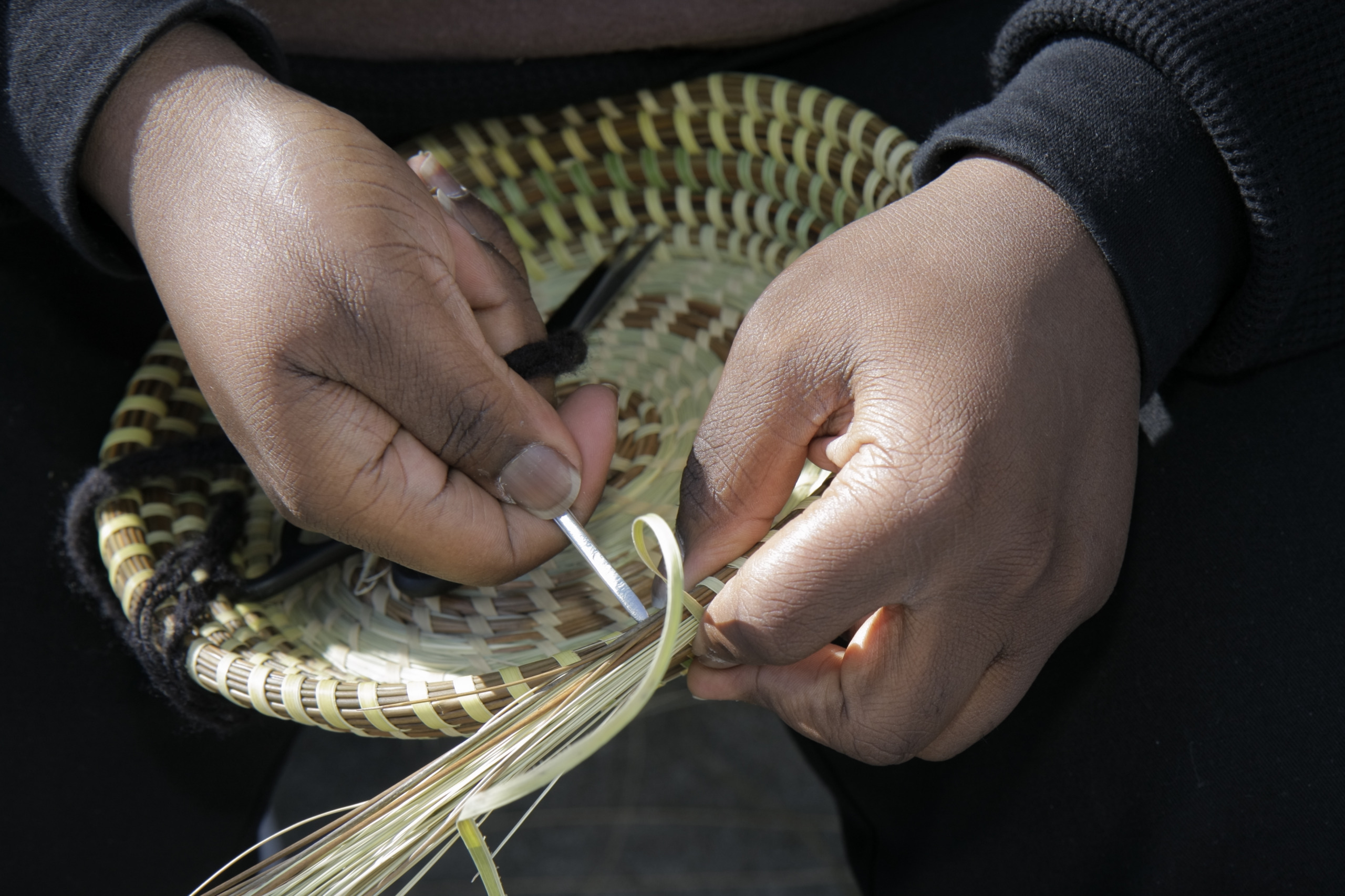 A close-up of hands weaving a sweetgrass basket. (Photo by: Jeffrey Greenberg/Universal Images Group via Getty Images)