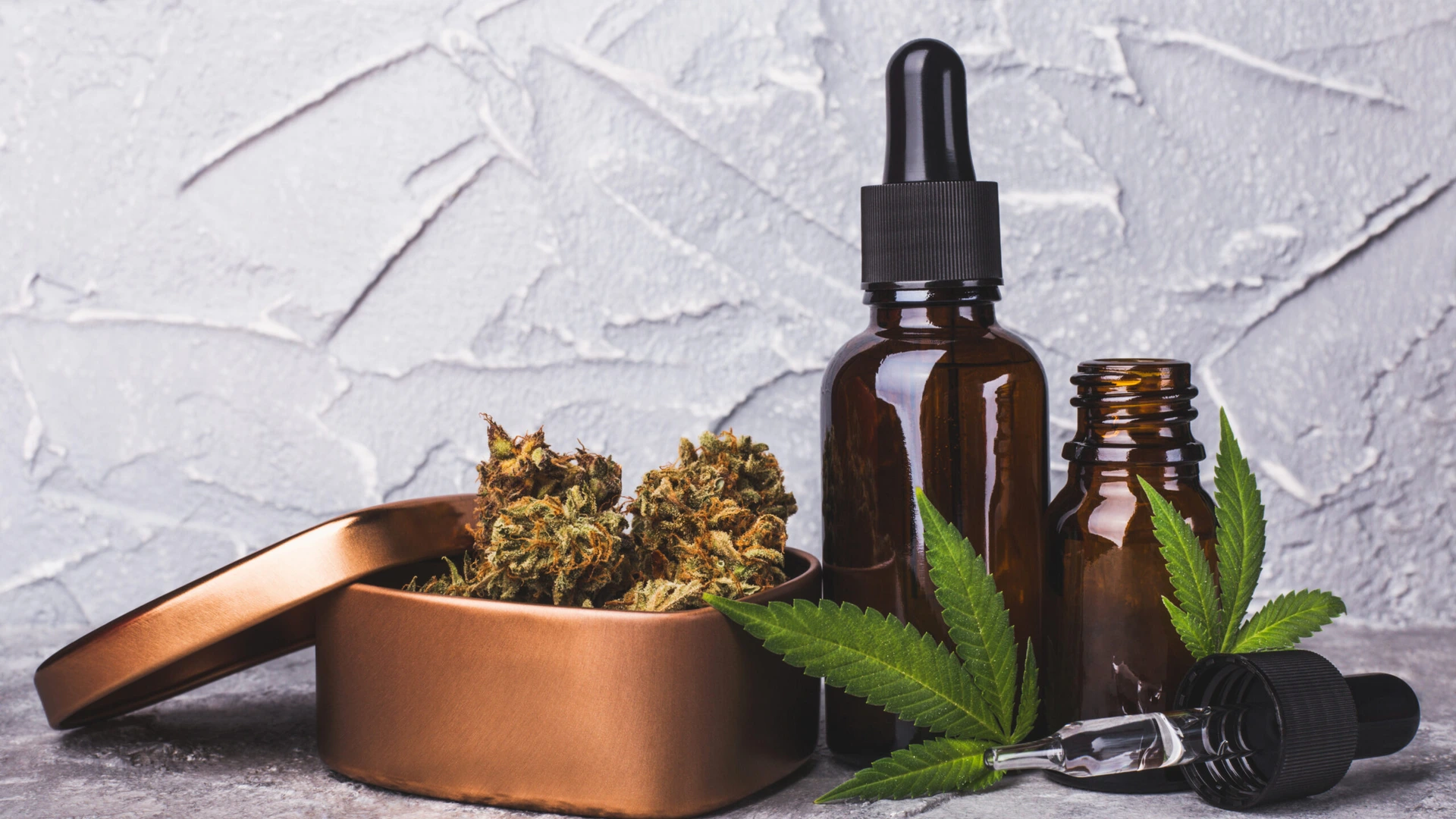 Cannabis CBD oil extracts in jars near a slide of marijuana cones