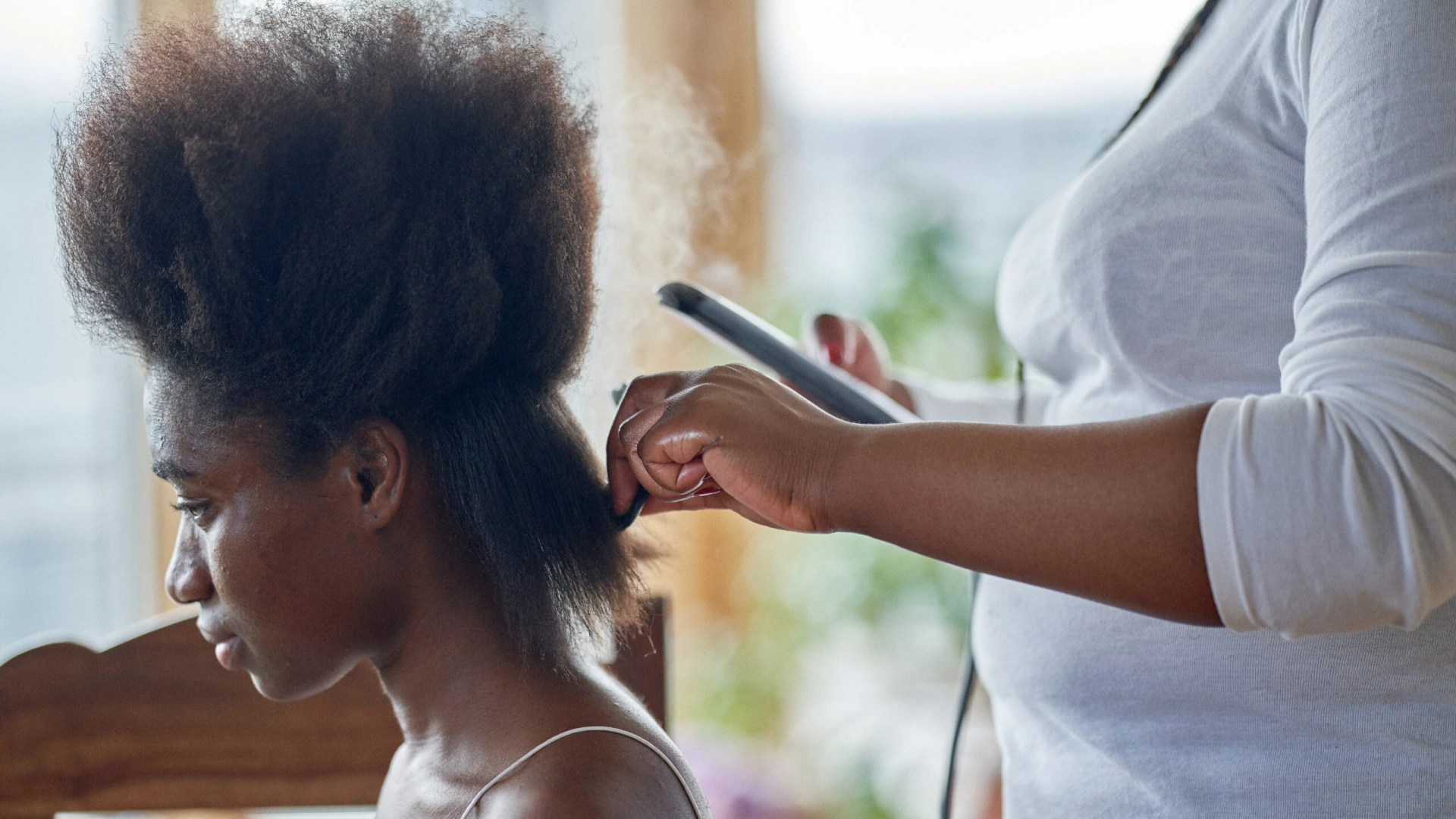 A young woman having her hair straightened. In preparation for hair braids