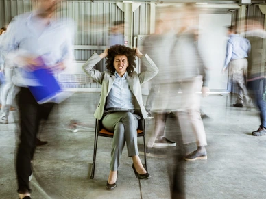 Frustrated African American businesswoman surrounded by her colleagues in blurred motion.