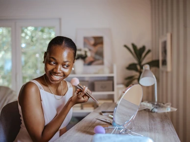Young black woman perfecting her makeup for prom