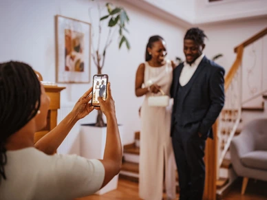 Mother taking pictures of her daughter and prom date, posing happily