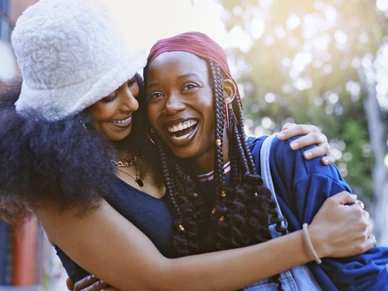 Happy, love and black lgbtq women hugging outdoors while on a walk in the city for fresh air. Happiness, smile and trendy lesbian african couple embracing and bonding together in an urban town.