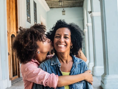 Portrait of mother receiving a kiss on the cheek from her daughter