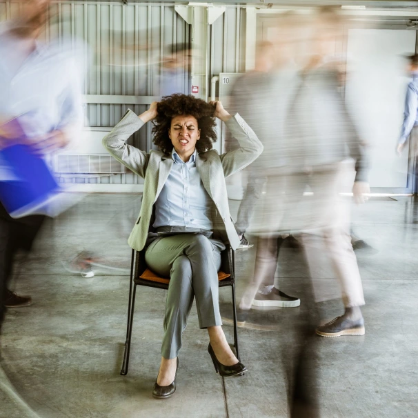Frustrated African American businesswoman surrounded by her colleagues in blurred motion.
